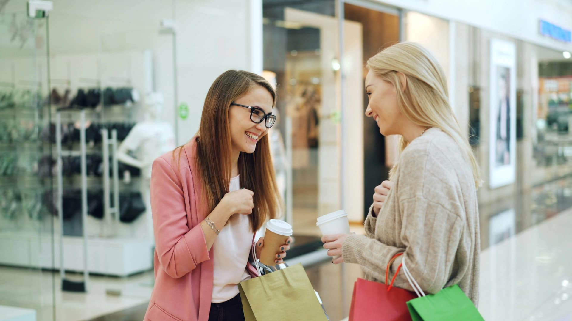 Two friends shopping together with coffee and bags