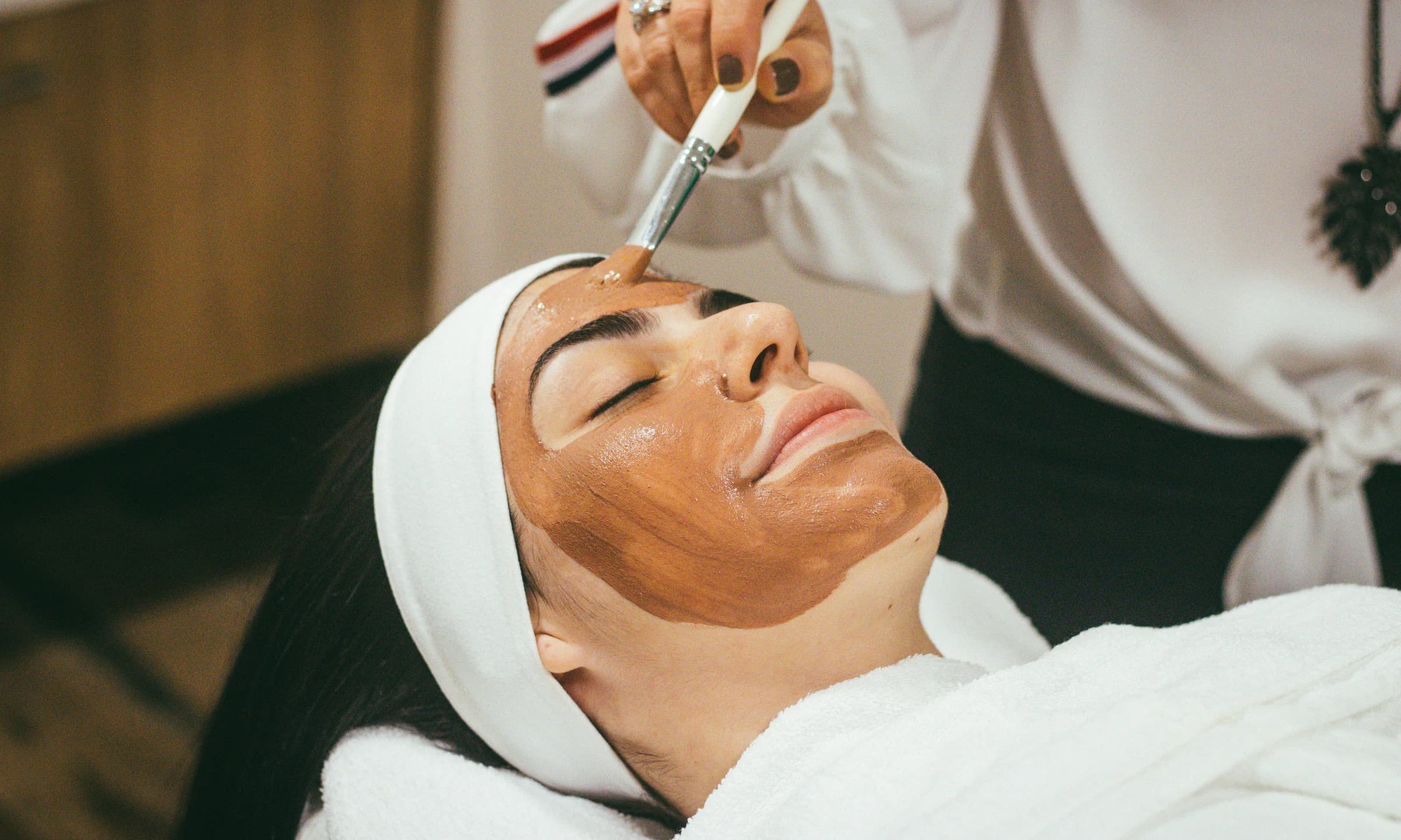 A beauty professional applying a facial treatment for a client